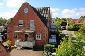 A two-story brick house with a balcony, a circular window, and a garage. - Rungholtstraße 6, Whg. 1 (Wyk auf Föhr)