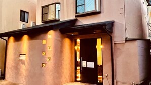 Ein Gebäude mit flacher Fassade, mehreren Fenstern und einem gut sichtbaren Eingang mit einer Tür.
