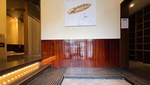 Eine Hotelhalle mit einer Holzwand, einem Schild mit der Aufschrift 'Shirahama No Kaze' und einem gefliesten Boden.