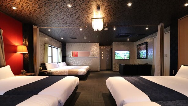 Ein Hotelzimmer mit zwei Betten, einem Fernseher, einem Schreibtisch und einer roten Wand.