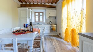 A kitchen with white cabinets, a wooden ceiling, a window with a view, and a table with chairs. - Stunning apartment in Borgo a Mozzano (Borgo a Mozzano)