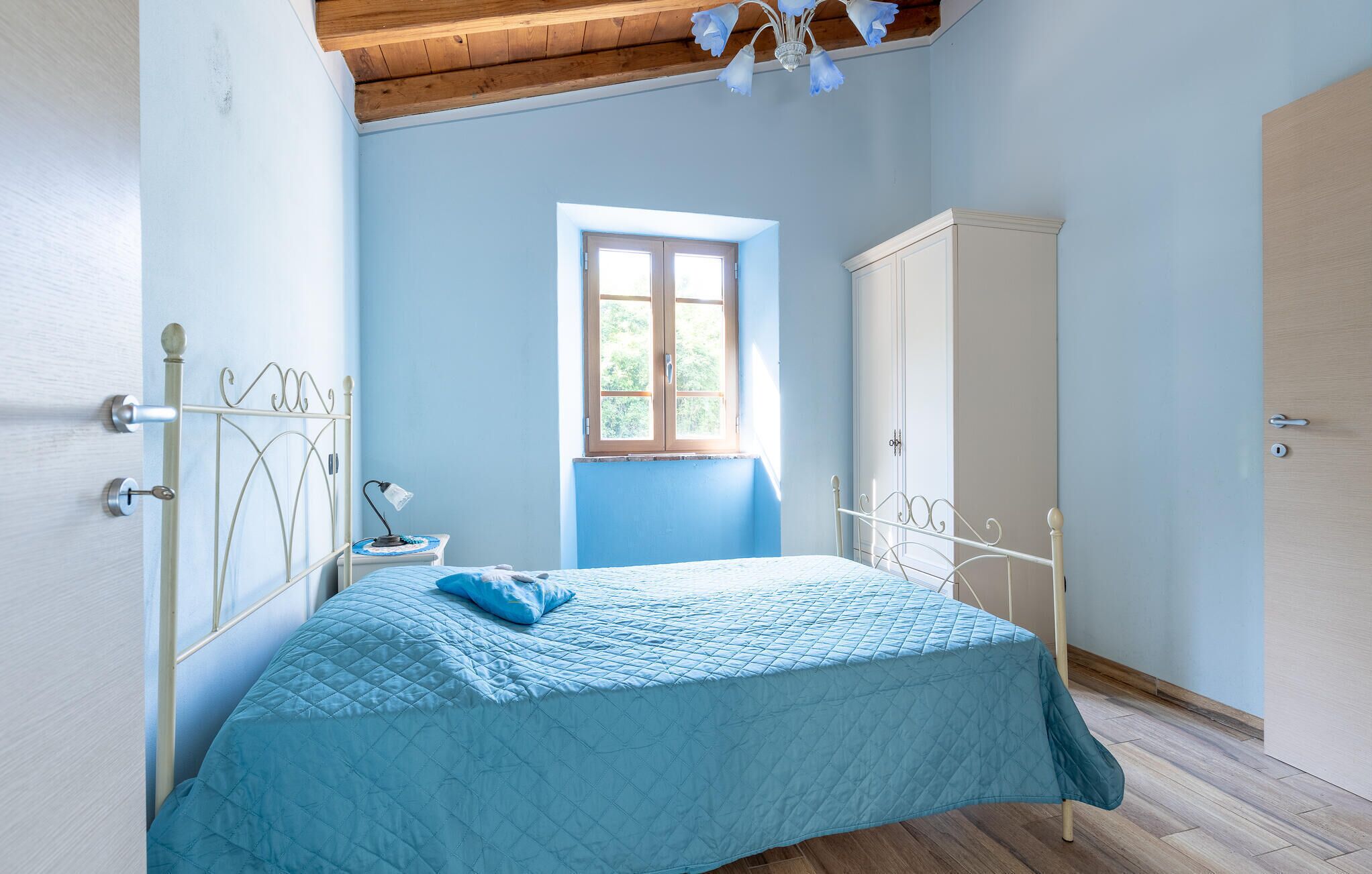 Een slaapkamer met een bed, een raam, een kledingkast en een deur.