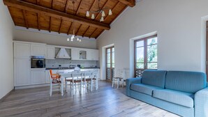 A spacious kitchen with white cabinets, a dining area with chairs, a blue sofa, and a wooden ceiling. - Stunning apartment in Borgo a Mozzano (Borgo a Mozzano)