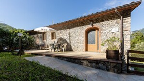 A stone building with a tiled roof, a wooden door, and a small outdoor seating area with a table and chairs. - Stunning apartment in Borgo a Mozzano (Borgo a Mozzano)