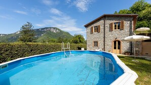 A stone building with a pool, surrounded by greenery and mountains. - Stunning apartment in Borgo a Mozzano (Borgo a Mozzano)
