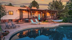 A two-story house with a pool, outdoor seating, and a covered patio area.
