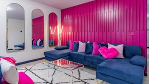 A modern living room with a sectional sofa, a glass coffee table, and a vibrant pink accent wall. - Sleek+ Modern Home Close to Downtown (Elizabethtown)