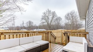 A wooden deck with a white outdoor sofa and a wicker bench. - Sleek+ Modern Home Close to Downtown (Elizabethtown)