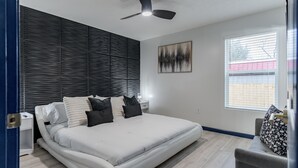 A modern bedroom with a bed, a ceiling fan, a window, and a nightstand. - Sleek+ Modern Home Close to Downtown (Elizabethtown)