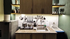 A modern kitchen with wooden cabinets, a granite countertop, and various kitchen utensils hanging on the wall. - Ocre Studio By Paradox (Panama City)