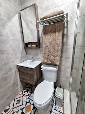 A bathroom with a toilet, sink, and shower. - Ocre Studio By Paradox (Panama City)