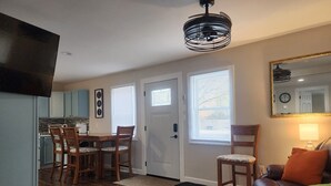 Ein modernes Wohnzimmer mit einer braunen Ledersofa, einem farbenfrohen Teppich und einem Essbereich mit Holzsesseln und einem Tisch.