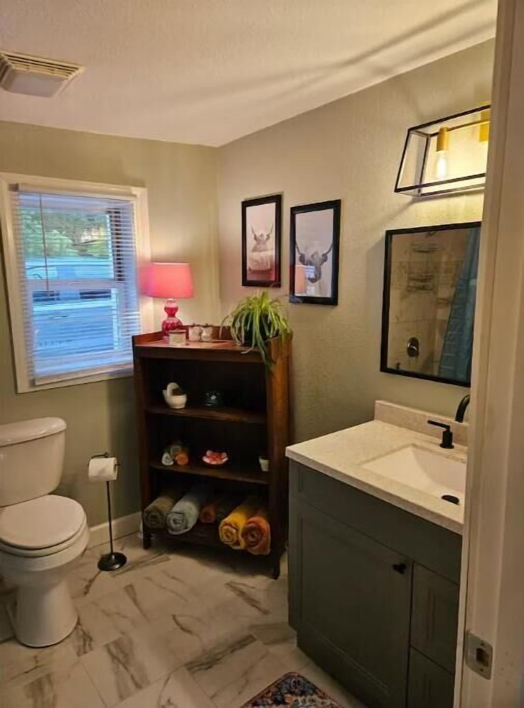 A compact bathroom with a toilet, sink, and a small shelf with decorative items.