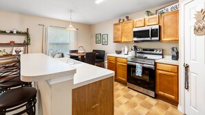 Une cuisine moderne avec des meubles en bois, un îlot central, un four à micro-ondes et un four traditionnel.