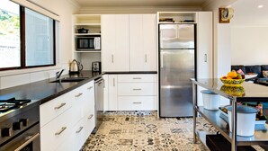 A modern kitchen with white cabinets, a stainless steel refrigerator, and a patterned floor. - Te Awanga-Zari House- Private&Quiet- 
Children & PETS welcome* (Upon agreement) (Te Awanga)