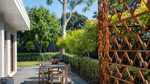 A patio with a table and chairs, a potted plant, and a wooden fence. - Te Awanga-Zari House- Private&Quiet- 
Children & PETS welcome* (Upon agreement) (Te Awanga)