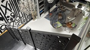 Un intérieur moderne avec un motif géométrique sur le mur, un luminaire sphérique suspendu et un coin salon agrémenté d’un coussin à motifs.
