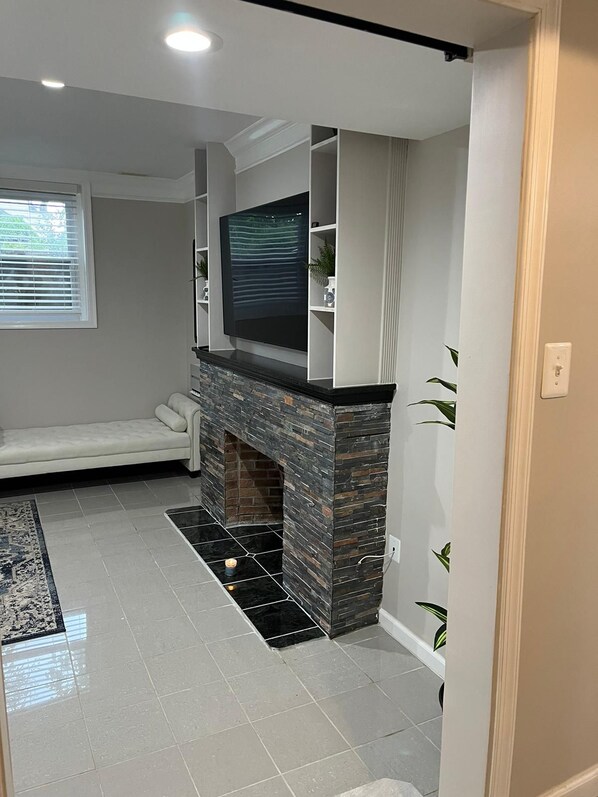 A modern living room with a fireplace, a sofa, and a television mounted on the wall.