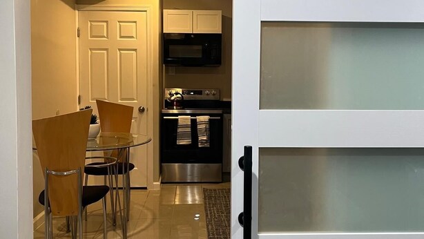 A modern kitchen with a dining area, featuring a glass door, stainless steel appliances, and a tiled floor. - Best Choice. Spacious, 1BR 1BA Apt in NW DC area with free street parking. (Washington)