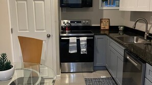 A modern kitchen with white cabinets, stainless steel appliances, and a glass dining table. - Best Choice. Spacious, 1BR 1BA Apt in NW DC area with free street parking. (Washington)