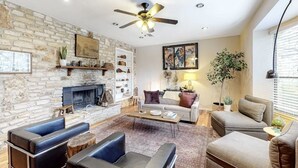 Una sala de estar con pared de piedra, chimenea, ventilador de techo y sofá.
