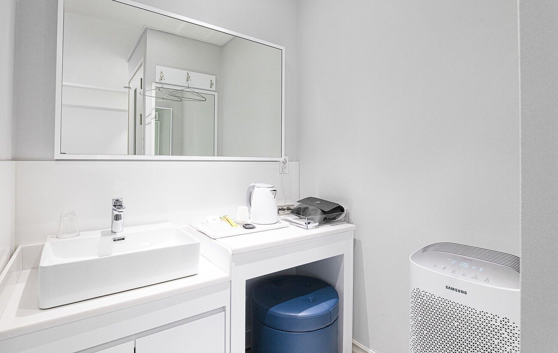 Une salle de bain moderne avec un lavabo blanc, un miroir et un purificateur d’air Samsung.