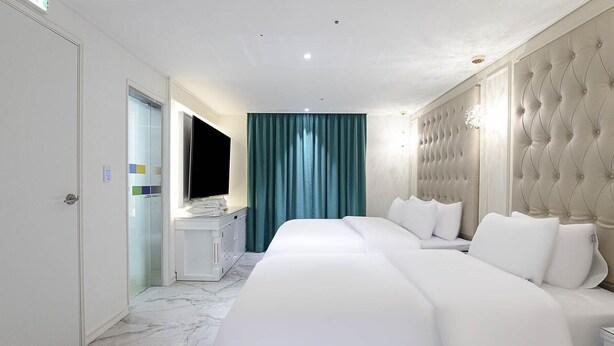 A hotel room with a large bed, a vanity with a mirror, and a television. - Star Light (Seoul)