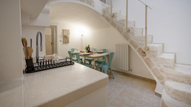 A kitchen with a dining area, a staircase, and a view of the outside. - GuestHost - La Mille - Charming Ostuni Apartment (Ostuni)