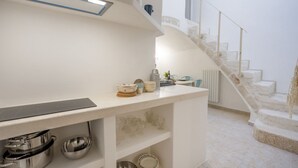 A modern kitchen with a built-in stove, a countertop with dishes, and a staircase leading to an upper level. - GuestHost - La Mille - Charming Ostuni Apartment (Ostuni)