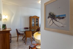 A dining area with a round table, chairs, a cabinet, and a painting on the wall.