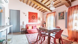 Una habitación acogedora con techo de madera, una mesa de comedor con sillas, un sofá y un tapete estampado.