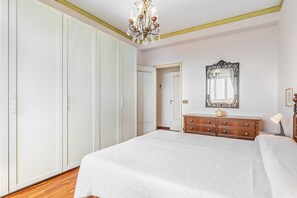 A bedroom with a large bed, a dresser, a mirror, and a wardrobe.