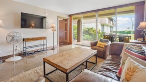 Una sala de estar moderna con una mesa de centro de madera, un sofá de cuero y un televisor de pantalla plana montado en la pared.