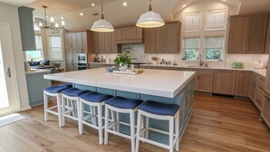 A spacious kitchen with a large island, wooden cabinets, and pendant lighting.