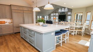 A spacious kitchen with a large island, wooden cabinets, and pendant lighting.