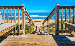 A wooden staircase leading to a beach with a clear view of the ocean.