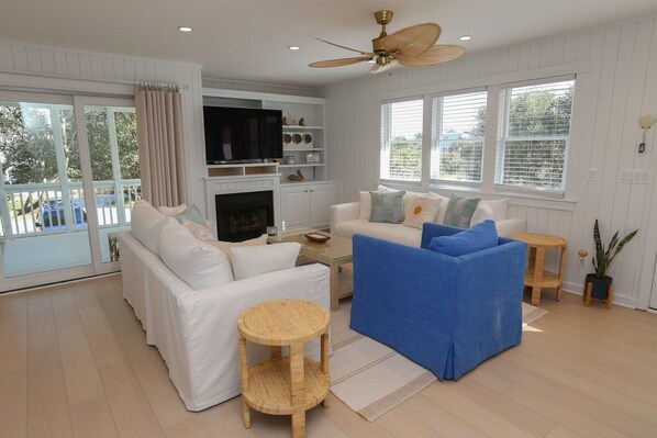 A living room with a white sofa, blue sofa, and a TV on a wooden shelf.