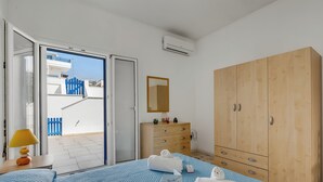 Ein Hotelzimmer mit Bett, einem Holzschrank, einem Nachttisch mit Lampe und Blick auf den Balkon.