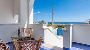 Ein Balkon mit Tisch und Stühlen, einer Flasche und Blick aufs Meer.