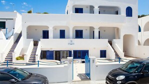 A white building with blue shutters, a staircase, and a gate.