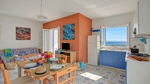 A cozy kitchen with a dining area, a TV, and a view of the sea.