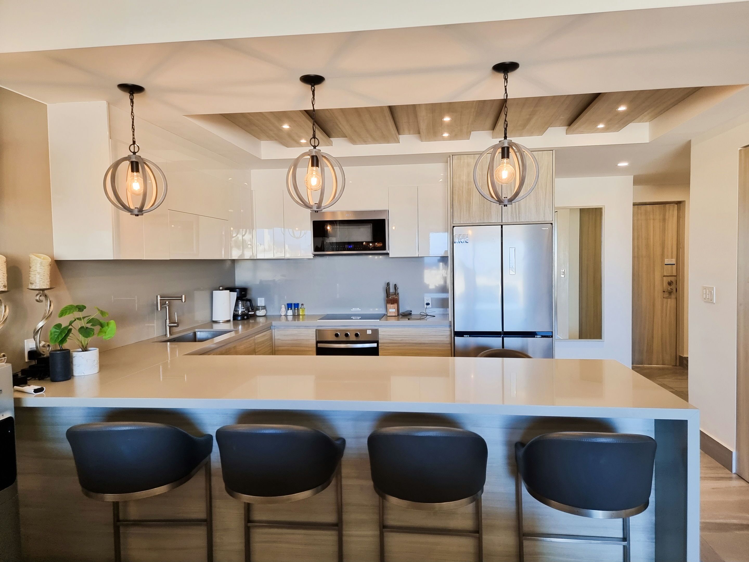 A modern kitchen with a central island, stainless steel appliances, and pendant lighting.