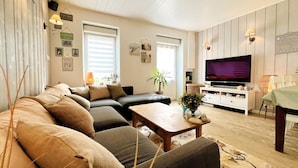 A living room with a sofa, a coffee table, a TV, and a dining area with a table and chairs. - The House of the Beach (Les Sables-d´Olonne)