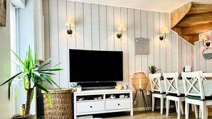 A modern living room with a flat-screen TV, white furniture, and decorative wall sconces. - The House of the Beach (Les Sables-d´Olonne)
