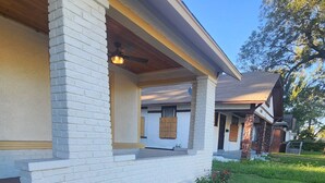 A two-story house with a covered porch, a brick exterior, and a well-maintained lawn.