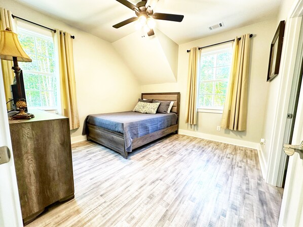 Un dormitorio con cama, ventilador de techo y ventana con cortinas.