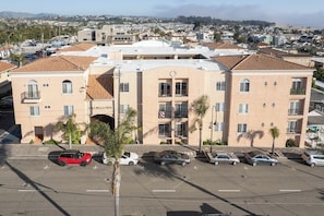 A multi-story building with a central entrance and a parking lot in front.