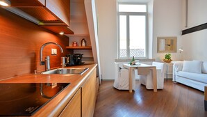 Une cuisine moderne avec des meubles en bois, un four encastré et un coin repas comprenant une table et des chaises blanches.