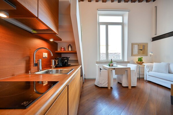 A modern kitchen with wooden cabinetry, a built-in oven, and a dining area with a white table and chairs.