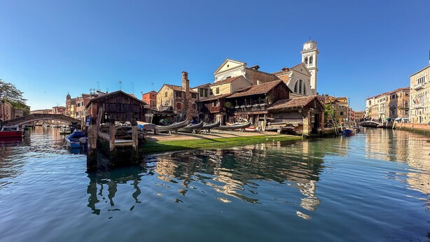 Un canal bordé de bateaux, de bâtiments historiques et d’un pont.